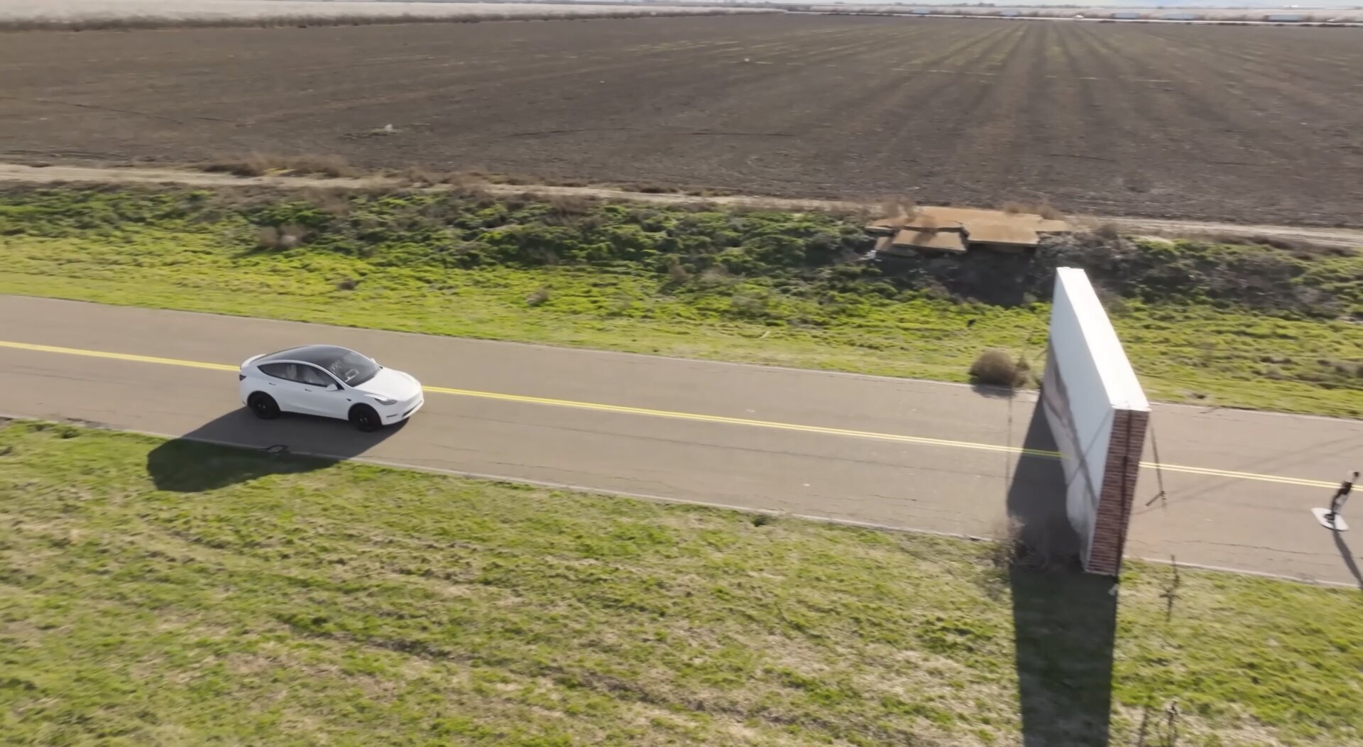 A Tesla drives toward a wall that is disguised to look like the road
